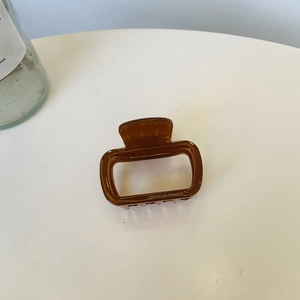 Detail of amber acetate hair claw clip with gold Creation France lettering on white background