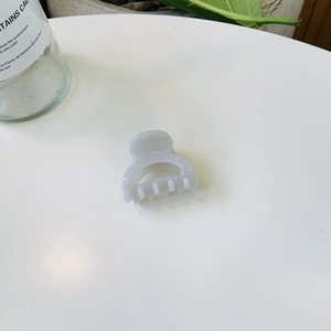 Vue détaillée d'une petite pince à cheveux en résine crème avec un design demi-cercle