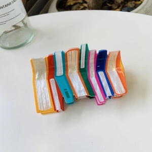 Pinza per capelli colorata a forma di libro in stile y2k su un tavolo bianco