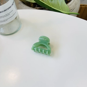 Vue détaillée de la pince à cheveux vert clair translucide sur surface blanche