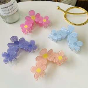 Detail of colorful acrylic flower hair claws in pink, blue, and purple on a desk