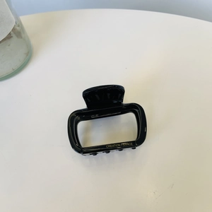 Detail view of the black acetate hair claw with Creation France gold lettering logo