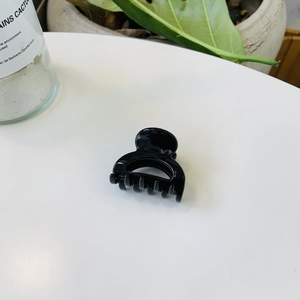 Gros plan sur une pince à cheveux noire brillante minimaliste sur une surface blanche élégante