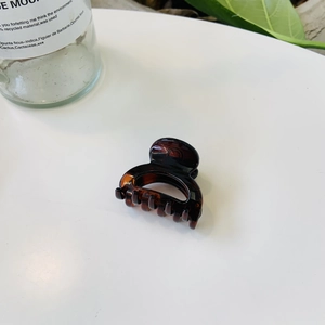 Gros plan sur une pince à cheveux motif tortue avec une texture ambre et marron au centre