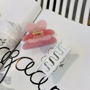 Détail de la pince à cheveux cœur rose et pince blanche ondulée à perles dorées