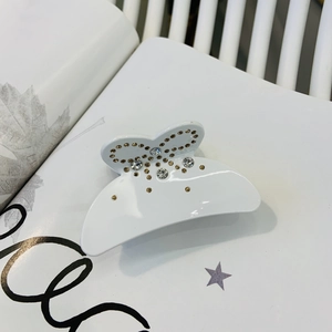 Détail d'une pince à cheveux papillon blanche ornée de strass brillants et de cristaux