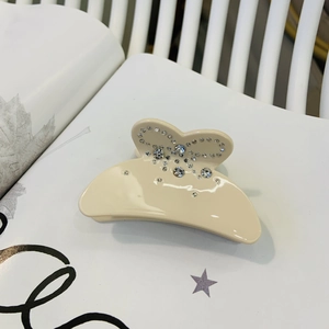 Détail d'une pince à cheveux en acétate crème avec motifs papillons en strass scintillants