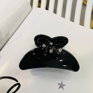 Pince à cheveux élégante en acétate noir avec strass flocons de neige sur un magazine