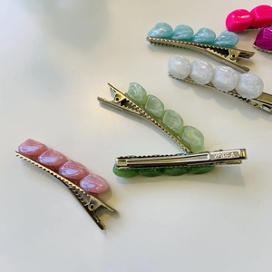 Dettaglio di fermagli colorati in resina con trama marmorea e base a becco d'anatra