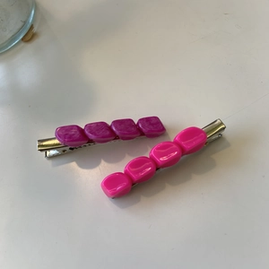 Dettaglio di fermagli per capelli in resina marmorizzata viola e rosa con base metallica