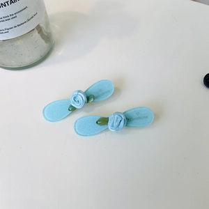Detail view of two light blue satin rose hair clips on translucent glitter acetate base