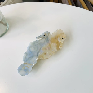 Macro detail of dual-tone seahorse hair claw made from premium pearlescent acetate material