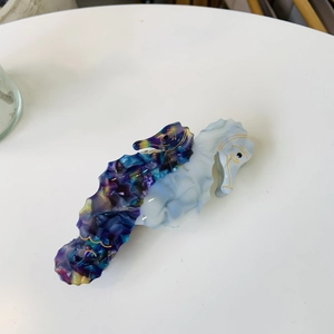 Detail of dual seahorse hair claw clip with colorful marble patterns and golden accents