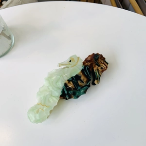 Detail of seahorse hair claw clip with dual-tone acetate finish and gold outline