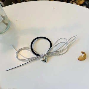 Vue détaillée du pendentif cœur argenté sur chouchou noir avec nœud en ruban métallique chic