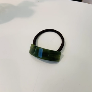 Détail d'un élastique en acétate vert foncé avec texte France Handmade sur blanc