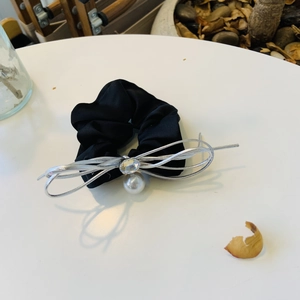 Détail du chouchou en soie noire avec nœud argenté, perle de cristal et perle blanche