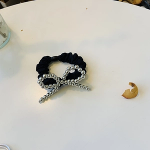 Détail d'un chouchou en soie noire avec un nœud orné de perles argentées étincelantes