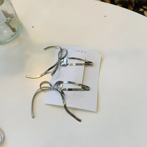 Gros plan de barrettes à cheveux à nœuds argentés sur carte, accessoire élégant en métal