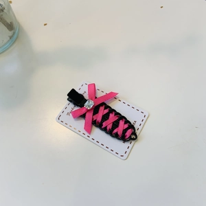 Pink ribbon bow hair clip with rhinestone accent on black seamless duckbill pin
