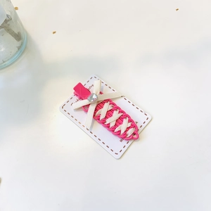 Detail of rose red bow hair clip with white ribbon lacing and shiny square diamond