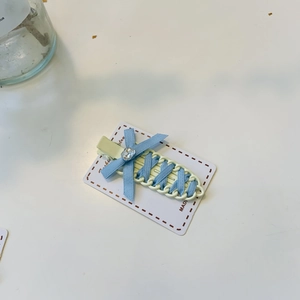 Detail of light blue bow hair clip with crystal rhinestone on white jewelry card