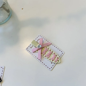 Detail of pink ribbon bow hair clip with faux diamond on a cream duckbill base