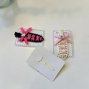 Detail view of pink bow hair clips with crystal accents on a white display card