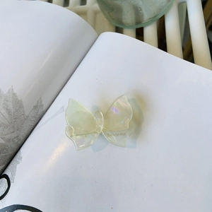 Dettaglio di un fermaglio per capelli a farfalla in acetato bianco con scritta SANSHINE