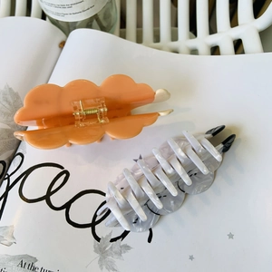 Detailed shot of acetate hair claws in marble grey and translucent orange on a magazine