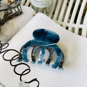 Dettaglio del fermaglio per capelli marmorizzato blu con molla in metallo