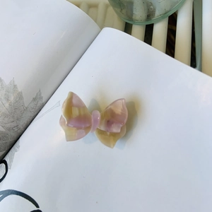 Dettaglio del fermaglio a farfalla in acetato con trama marmorizzata rosa e gialla