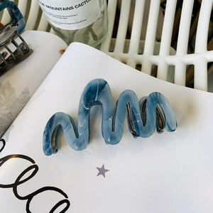 Dettaglio della pinza per capelli a onda con trama marmorizzata blu in acetato premium