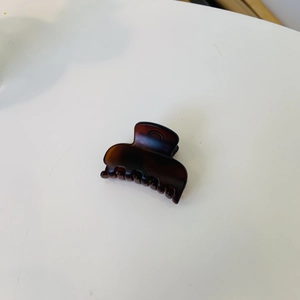 Vue détaillée d'une mini pince à cheveux carrée en résine brune avec ressort métallique