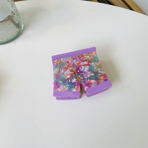 Détail d'une pince à cheveux en acétate violet en forme de short avec texture marbrée