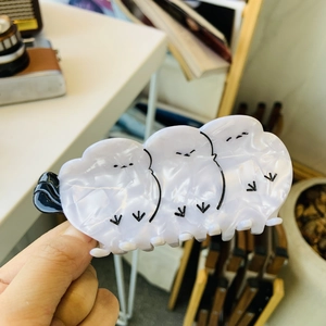 Close-up of a large white acetate hair claw clip featuring three cute minimalist black birds