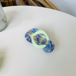 Vue détaillée d'une pince à cheveux forme pantoufle avec motif marbré et petits strass