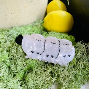 Detail of white acetate hair claw clip with cute bird design on green moss background