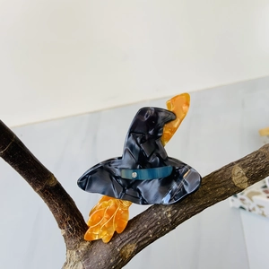 Acetate hair claw clip featuring a black witch hat and orange broom for Halloween