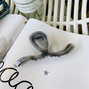 Dettaglio della molletta per capelli grigio fumo con design a onde e denti neri