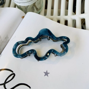 Elegante molletta ondulata con trama in marmo blu su sfondo di rivista minimalista