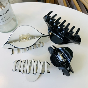 Détail d'un lot de quatre pinces à cheveux en acétate noir et crème de différentes tailles
