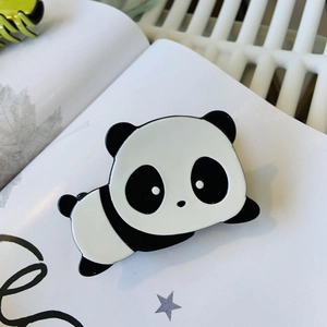 Pinza para el pelo de acetato con forma de panda sobre un libro para accesorios de moda