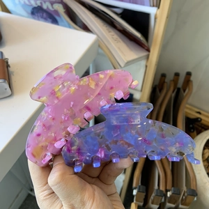 Pince à cheveux en acétate motif marbre rose et bleu présentée dans un décor de style de vie