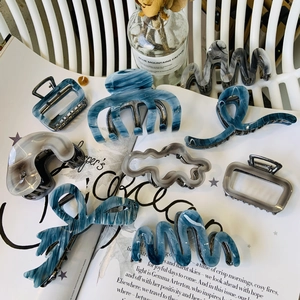 Dettaglio di mollette per capelli in acetato blu con trama marmorizzata e onde