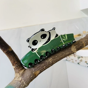 Detalle de una pinza para el pelo de panda con motivos de bambú sobre una rama de madera