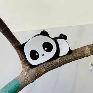 Detalle de pinza para el pelo con forma de panda en acetato sobre rama decorativa
