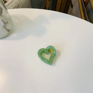 Détail de la pince à cheveux cœur vert avec mécanisme à ressort en métal doré