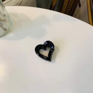 Gros plan d'une pince à cheveux noire brillante en forme de cœur sur fond blanc
