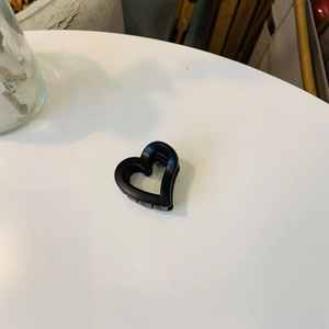 Vue de dessus d'une pince à cheveux mate noire en forme de cœur creux sur fond blanc